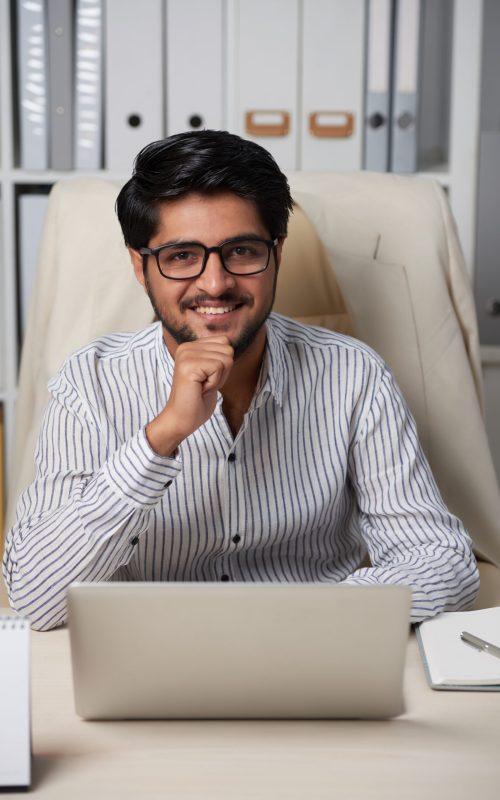 Portrait of Indian handsome business executive sitting at table